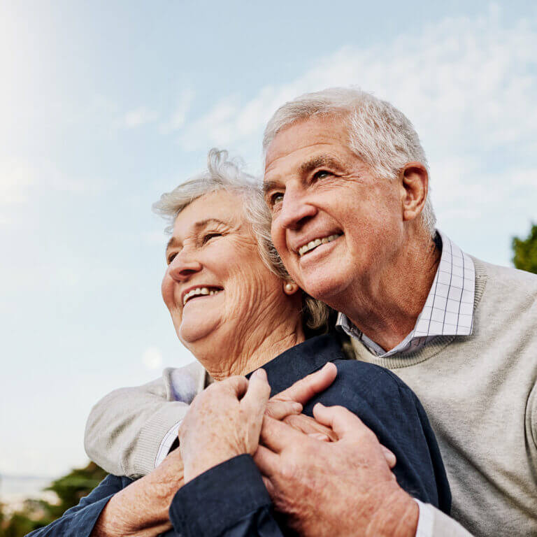 A smiling older couple embracing outdoors
