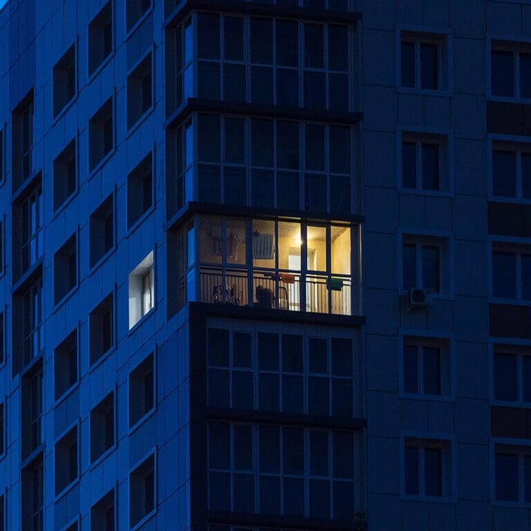 A single lit office window in a dark tower block at night