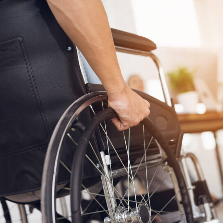 A person’s hand on the wheel of a wheelchair