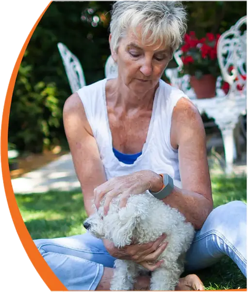 Picture of woman wearing Acticheck life-saving wristband in garden playing with her dog